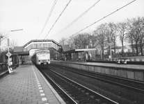 150439 Gezicht op perrons, voetgangersbrug en sporen van het N.S.-station Hilversum N.O.S. te Hilversum met langs het ...
